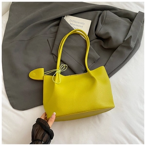 Macro shot of lime green pebbled leather tote bag with a heart charm and slender strap