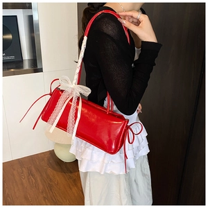 Détail d'un sac à bandoulière rouge brillant avec nœud en dentelle et rubans de côté