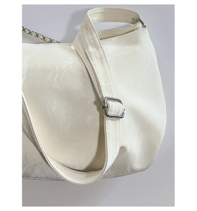 Detail of white marble textured leather shoulder bag with wide strap and silver metal buckle