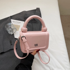 Vue détaillée du sac à main rose avec une poignée ronde rigide et un logo en métal élégant