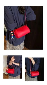 Close-up of red cylindrical bag with litchi grain leather and colorful letter pendant
