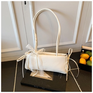 Détail d'un sac à bandoulière crème avec nœud en dentelle blanche et anse tressée