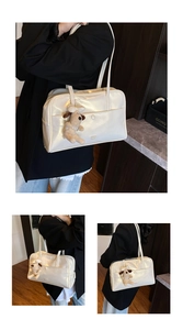 Detailed view of glossy cream-white tote bag with a cute plush dog charm decoration