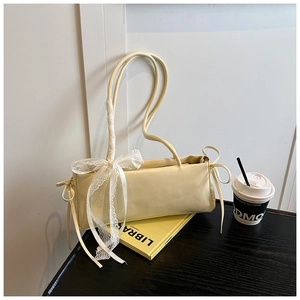 Détail d'un sac à main crème avec ruban en dentelle sur la poignée et cordons décoratifs