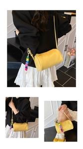 Detail view of yellow cylindrical leather barrel bag with vibrant acrylic letter charm