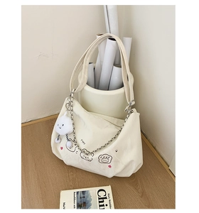 Detailed shot of white canvas tote bag with cartoon bears and cloud plush charm