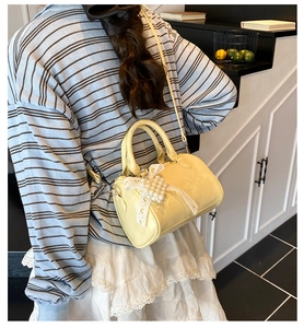 Detail of light yellow mini Boston bag with lace pearl bow charm and adjustable strap