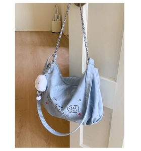 Detail of light blue tote bag with poppy cartoon illustration and silver chain strap