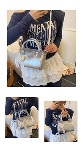 Detail view of silver metallic Boston bag with pearl heart pendant and lace bow accents