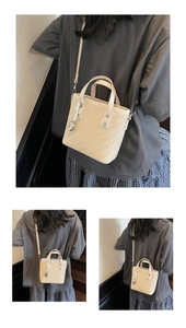 Detail der cremefarbenen geflochtenen Eimertasche mit silbernem Herzanhänger und Schultergurt