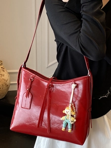Chic red patent leather tote bag with glossy finish and cute pearl doll charm accessory