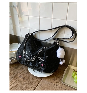 Detail of black tote bag with wrinkled texture, cartoon cat print and plush charm