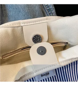 Detail of magnetic snap closure and zipper pocket inside a canvas tote bag