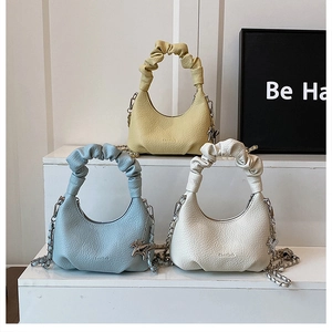 Close-up of three ruched cloud bags in yellow, blue and white with silver chain straps