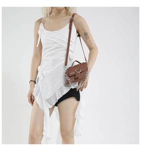 Détail du sac en cuir marron avec grande boucle métallique et bandoulière chaîne