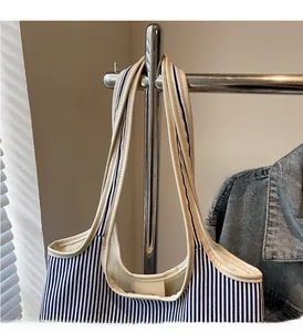 Detail of blue and white striped canvas tote bag showing durable beige handles and stitching