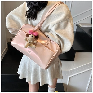 Detail of light pink patent leather shoulder bag with cute puppy plush charm accessory