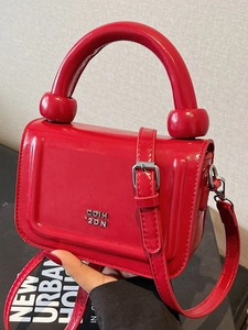 Sac à main carré en cuir rouge brillant avec poignée et logo argenté sur fond clair épuré