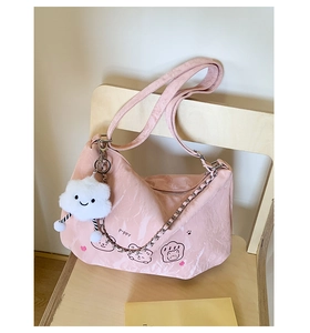 Pink poppy cloud bag detail with plush cloud charm and metallic chain strap on wooden chair