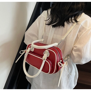 Detail showing red vintage leather backpack with white bow accents and adjustable strap