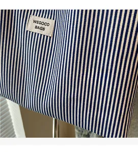 Close-up of blue striped canvas fabric texture and white branded woven label on tote bag