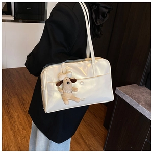 Detail of white glossy PU shoulder bag with a cute plush puppy pendant and pearl detail