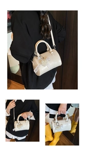 Detail of cream white patent leather Boston bag with unique pearl bow charm and straps