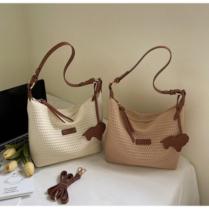 Close-up of woven straw tote bag with brown faux leather straps and elephant charm