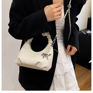 Close-up of beige ruched hobo bag with silver horse charm and chain strap detail