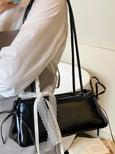 Sac bandoulière chic en cuir verni noir avec nœud en dentelle blanche et fines lanières