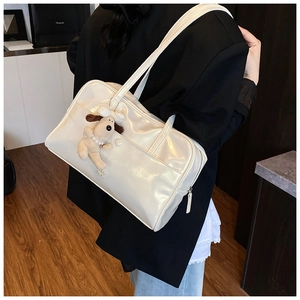 Detail of white glossy shoulder bag with plush puppy pendant and polished finish