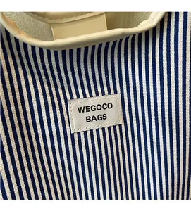 Detail of blue and white striped canvas tote bag showing the WEGOCO brand patch