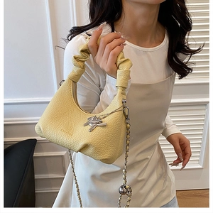 Detail of light yellow cloud bag featuring pleated handle and gold horse charm accessory