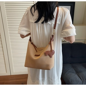 Detail of hand-woven straw tote bag with brown leather straps and cute charm