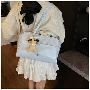 Detail of light blue glossy tote bag with a cute plush dog pendant and shoulder straps