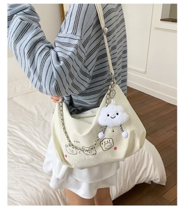 Detail of white canvas tote bag with cat print and plush cloud charm accessory
