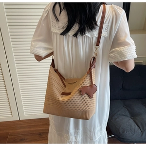 Detailed texture of beige woven straw hobo bag with brown faux leather strap and sheep charm