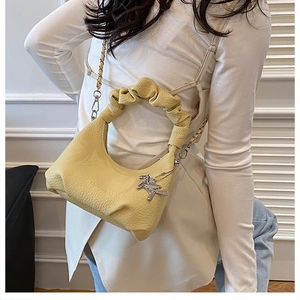 Detail of light yellow cloud bag with pleated handle and silver horse pendant charm