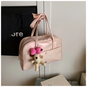 Detailed shot of pink glossy PU leather pillow bag with cute plush dog pendant and strap