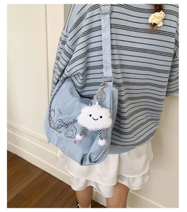 Close-up of light blue pleated nylon shoulder bag with silver chain and cloud plush charm