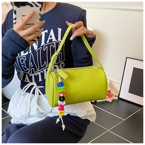 Detail of neon green pillow bag featuring lychee grain leather and colorful bead charm