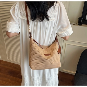 Detail of hand-woven beige tote with brown leather strap and cat charm on white lace dress