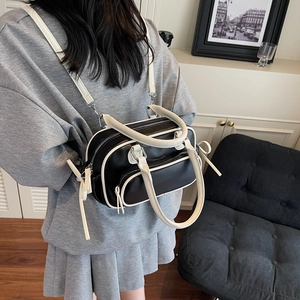 Detailed view of bicolor Boston bag featuring contrast handles and tassel zipper detail