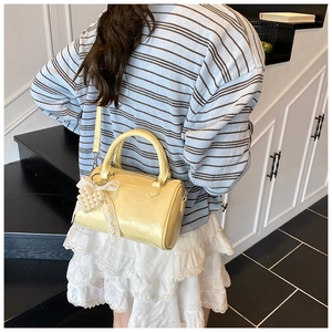 Detail of light yellow Boston bag with glossy wrinkled leather and pearl lace pendant