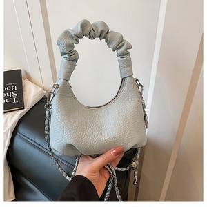 Detail showing light blue pleated cloud handle and silver chain on lychee leather bag