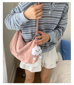 Detailed close-up of pink crescent shoulder bag with cute cartoon bear prints and charm