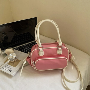 Close-up of pink nylon crossbody bag with cream trim and side drawstring bow detail