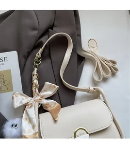 Détail du sac bandoulière en cuir PU blanc cassé avec nœud en soie et pendentif peluche