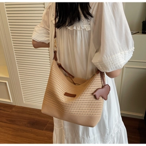 Detail of woven straw tote bag with brown leather straps and a horse-shaped leather charm