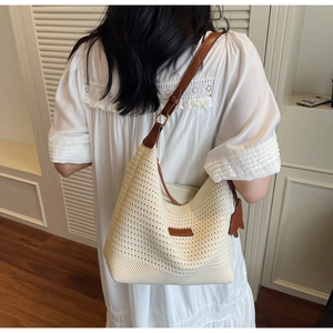 Detail of a cream woven tote bag with brown leather strap worn by a model in soft light